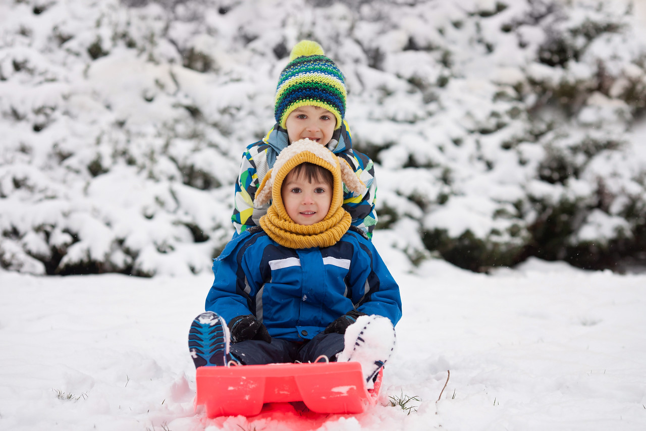 Two kids sledging in the snow